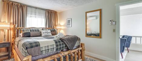 A bedroom with a wooden bed frame, a large mirror, and a view of the balcony.