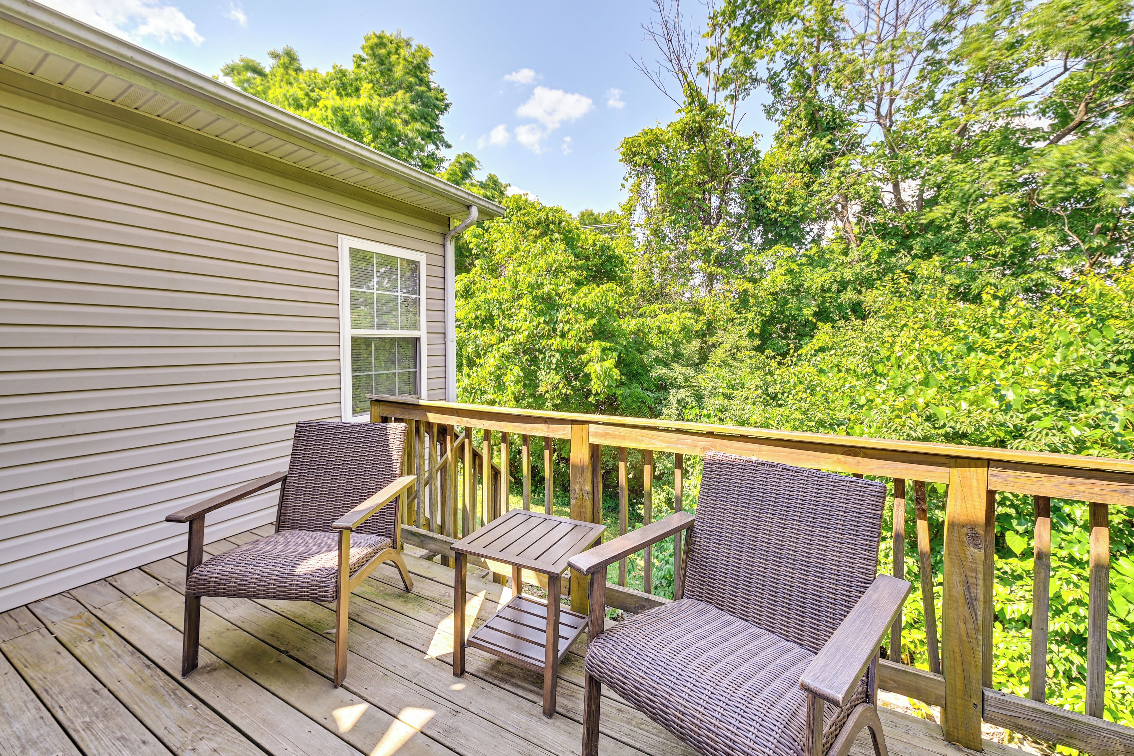 A wooden deck with wicker furniture and a view of a lush green forest.