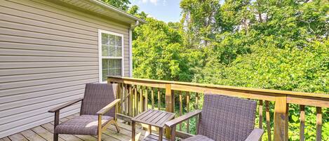 A wooden deck with wicker furniture and a view of a lush green forest.