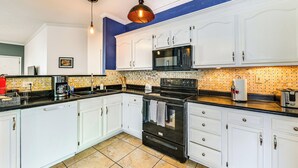 Een moderne keuken met witte kasten, een zwarte kookplaat en een magnetron.