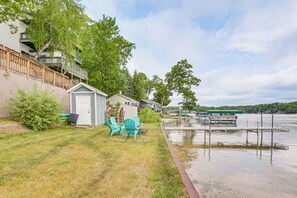 A lakeside property with a grassy yard, a small shed, and a dock extending into the water. - Dock + Views: Scenic Lakefront Escape in Harrison (Harrison)