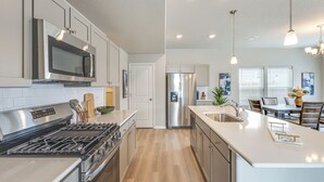 Una cocina moderna con electrodomésticos de acero inoxidable, una isla central e iluminación colgante.