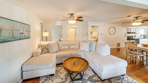 A modern living room with a sectional sofa, a coffee table, and a dining area with wooden chairs and a table.