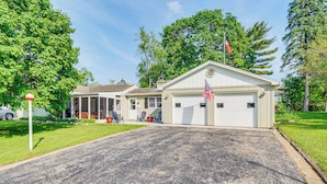 A residential garage with an American flag, a covered porch, and a well-maintained lawn.