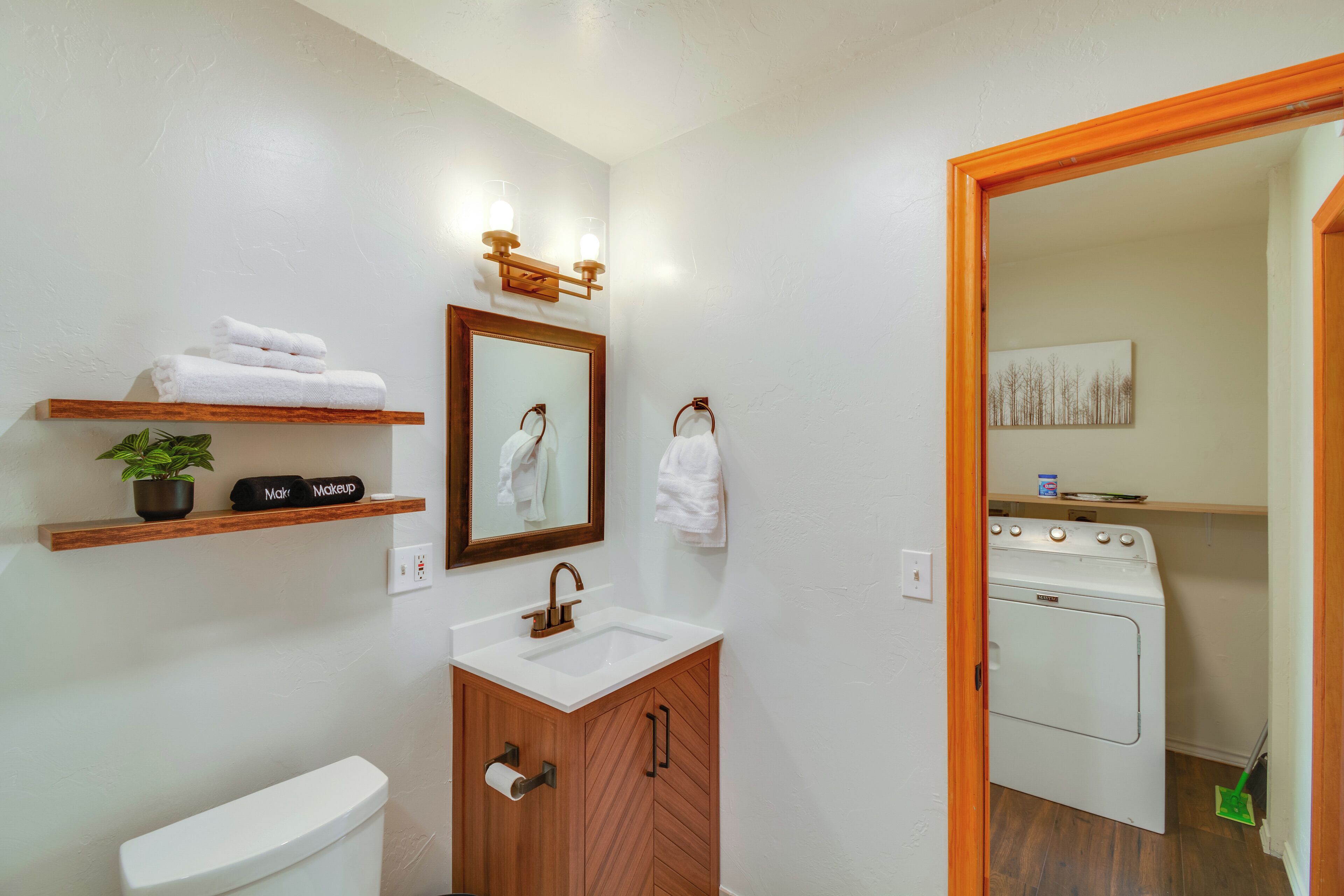 A bathroom with a toilet, sink, mirror, towel rack, and a wooden cabinet.