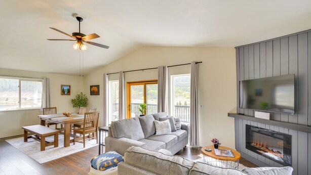 A spacious living room with a grey sofa, a wooden dining table with chairs, a ceiling fan, and a fireplace. - Hike, Fish, Ski & Explore: Cabin Near Breckenridge (Alma)