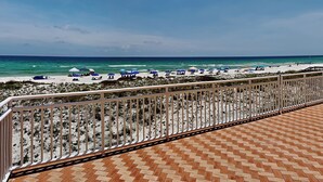 Une vue sur la plage depuis un balcon doté d’un sol carrelé et d’une rambarde en métal.