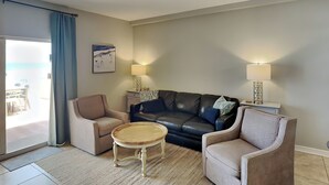 A living room with a ceiling fan, two sofas, a coffee table, and two lamps. - Sans Souci 102 | Gulf-Front, Large Patio + Seasonal Beach Service (Pensacola Beach)