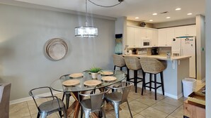 A modern kitchen with white cabinets, a microwave, and a refrigerator. - Sans Souci 102 | Gulf-Front, Large Patio + Seasonal Beach Service (Pensacola Beach)