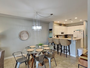 A modern kitchen with white cabinets, a microwave, and a refrigerator. - Sans Souci 102 | Gulf-Front, Large Patio + Seasonal Beach Service (Pensacola Beach)