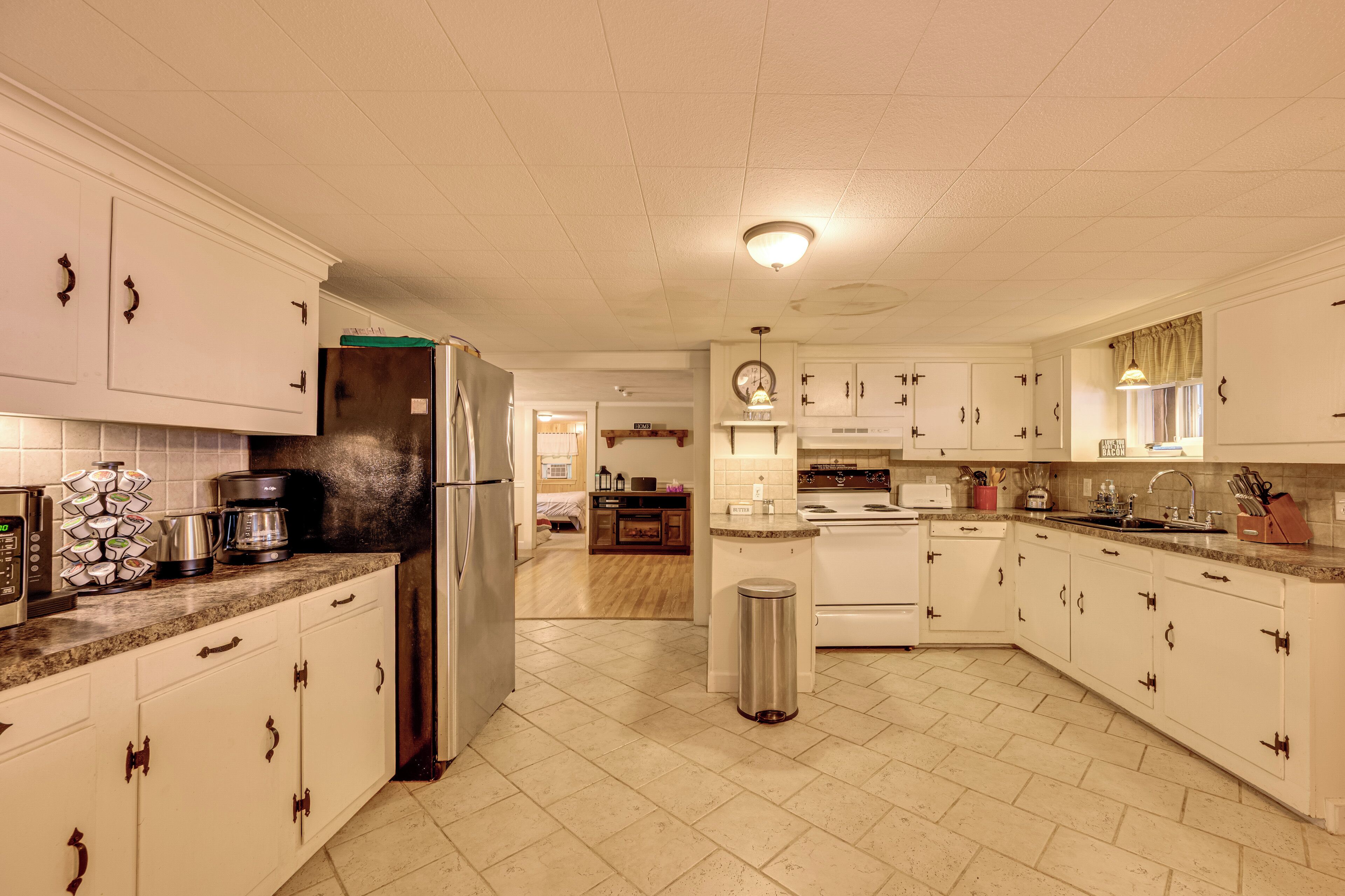 A spacious kitchen with white cabinets, a stainless steel refrigerator, and a tiled floor.