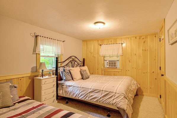 A bedroom with a bed, a dresser, a window with curtains, and wooden paneling. - Home w/ Outdoor Entertainment Area in Ashland! (Ashland)