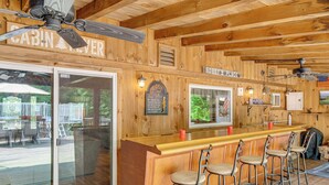 Un bar de estilo cabaña con paredes de madera, barra y cuatro taburetes.