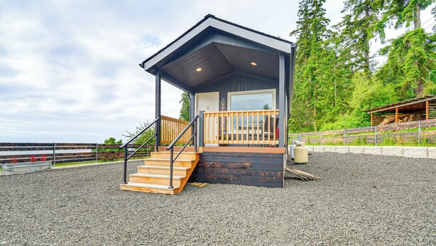 Ein kleines Holzhaus mit Veranda, Holzstufen und Kiesgrundstück.