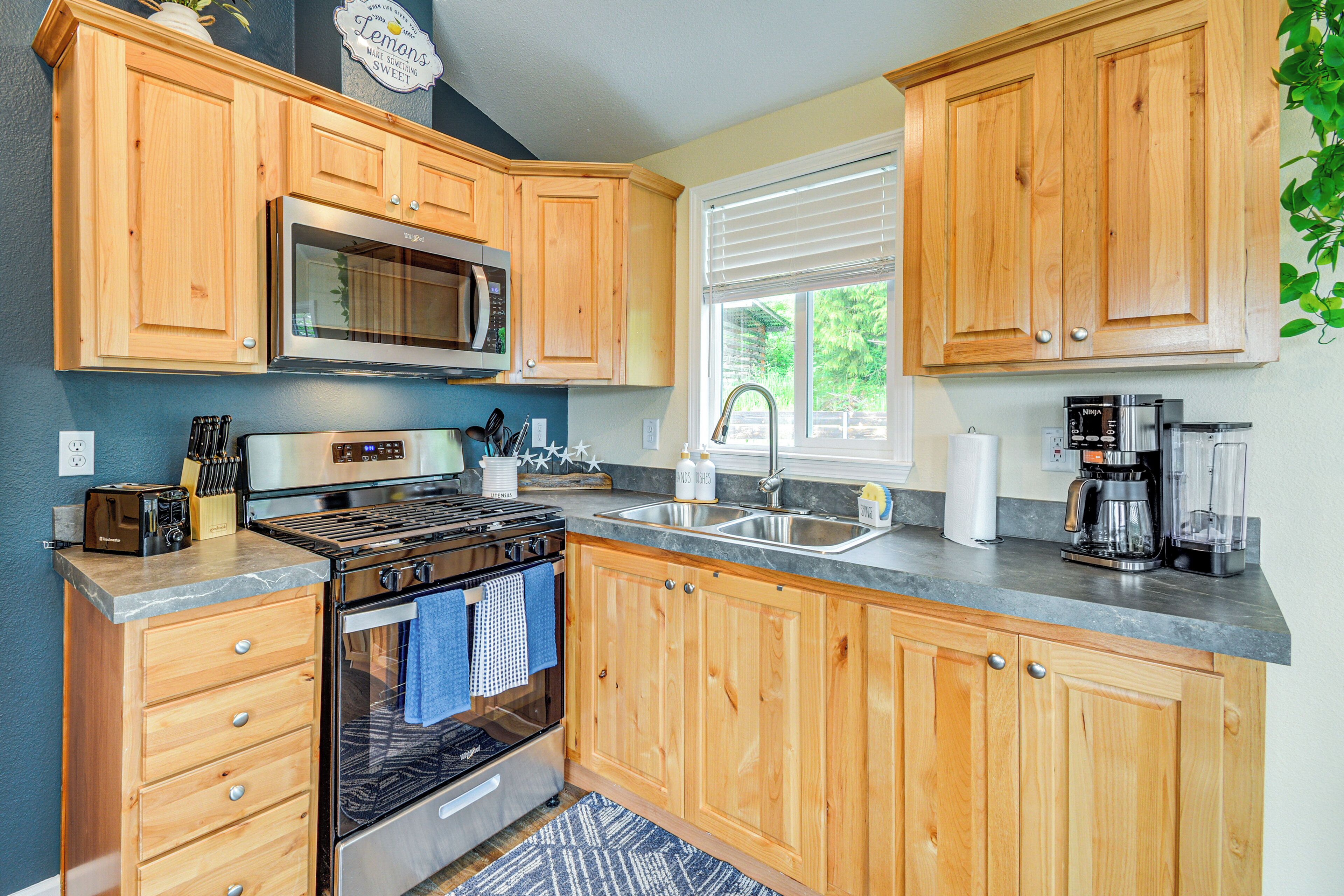A kitchen with wooden cabinets, a stainless steel oven, a microwave, and a sink.