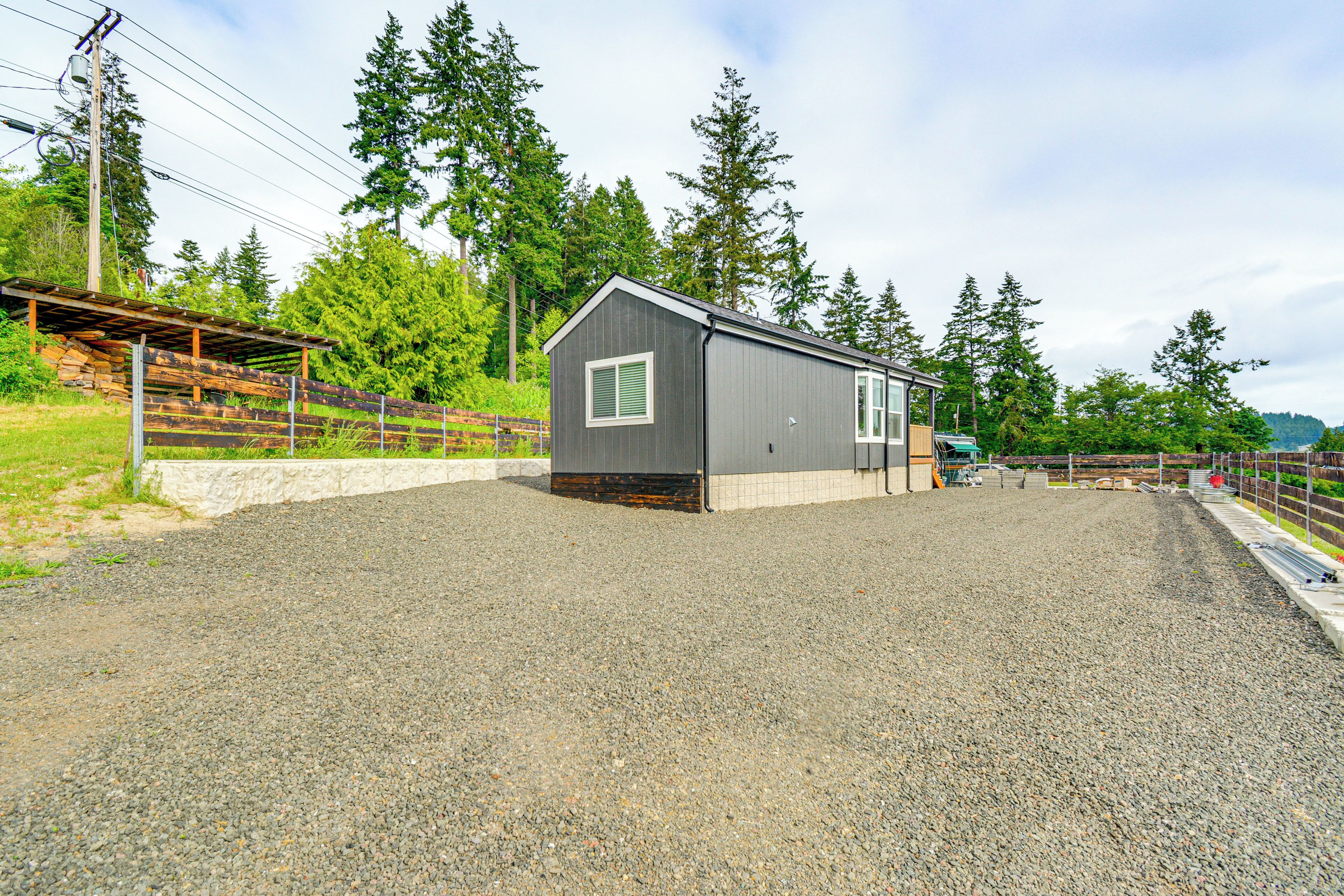 A gravel-covered area with a small, single-story building with a sloped roof and a window.