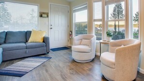 Ein Wohnzimmer mit grauem Sofa, beigem Sessel und blauem Teppich.