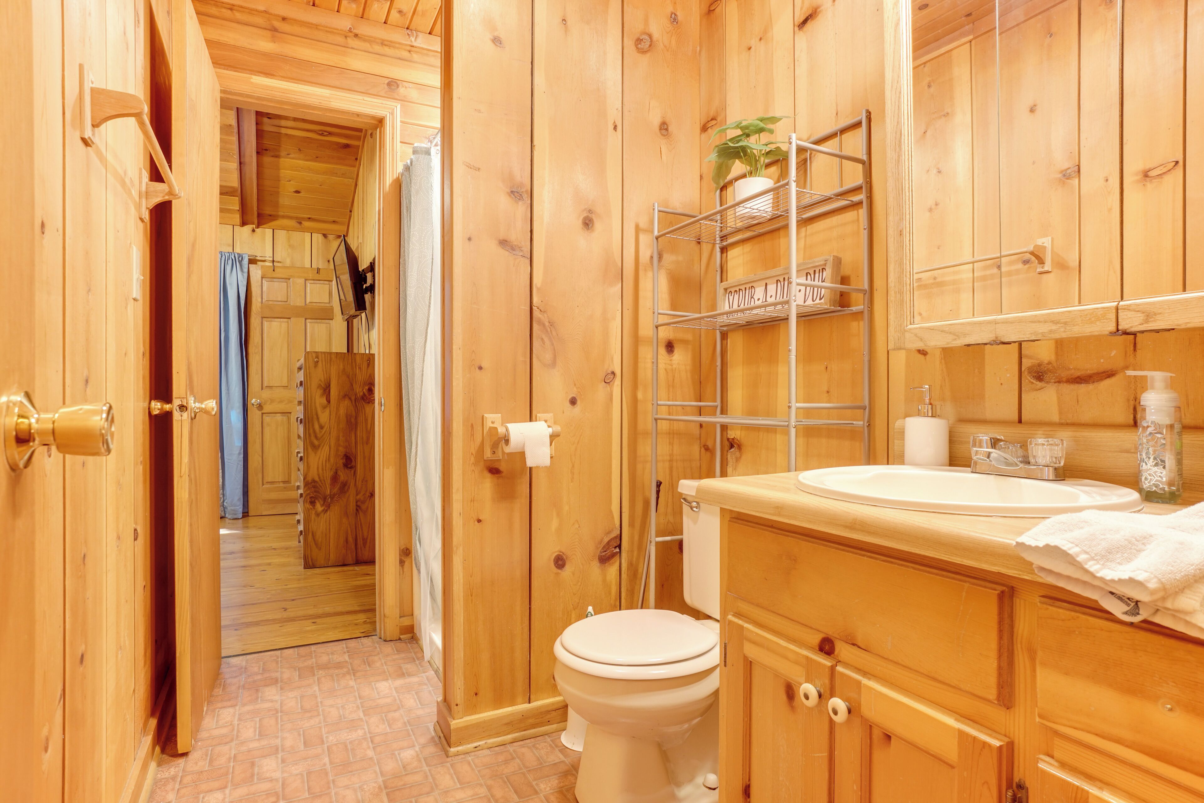 Un baño de madera con inodoro, lavamanos y estantes.