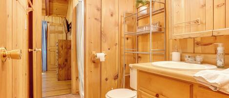Un baño de madera con inodoro, lavamanos y estantes.