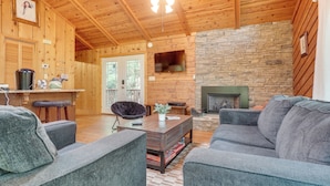 A cozy cabin interior with a stone fireplace, wooden walls, and a comfortable seating area. - Private Hot Tub & Game Room: Cleveland Getaway (Cleveland)