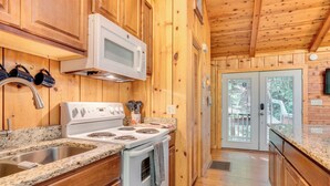 A wooden cabin kitchen with a white stove, a microwave, and a sink. - Private Hot Tub & Game Room: Cleveland Getaway (Cleveland)