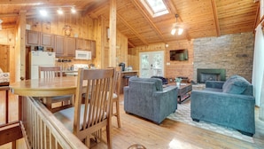 A wooden cabin interior with a dining area, kitchen, living room, and fireplace. - Private Hot Tub & Game Room: Cleveland Getaway (Cleveland)