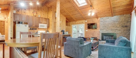 L’intérieur d’un chalet en bois comprend un coin repas, une cuisine, un salon et une cheminée.
