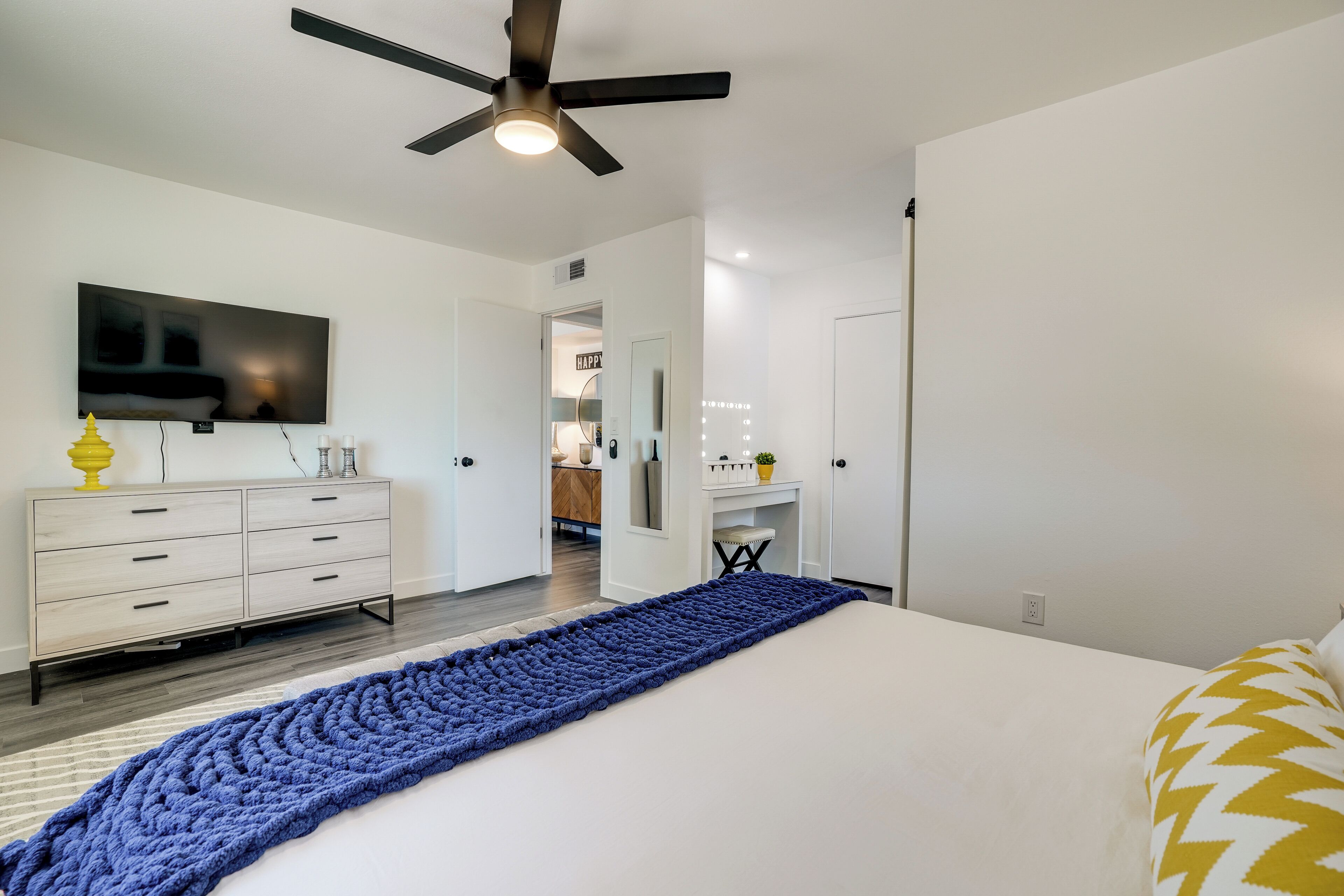Una camera da letto moderna con un letto grande, un ventilatore a soffitto, una TV e un comò.