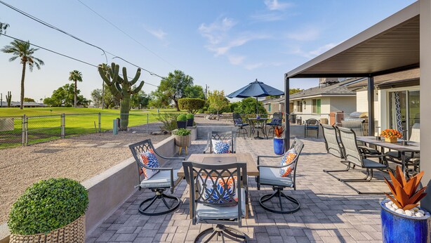 Ein Patio im Freien mit Sitzgelegenheiten, einem Tisch und einem überdachten Bereich.