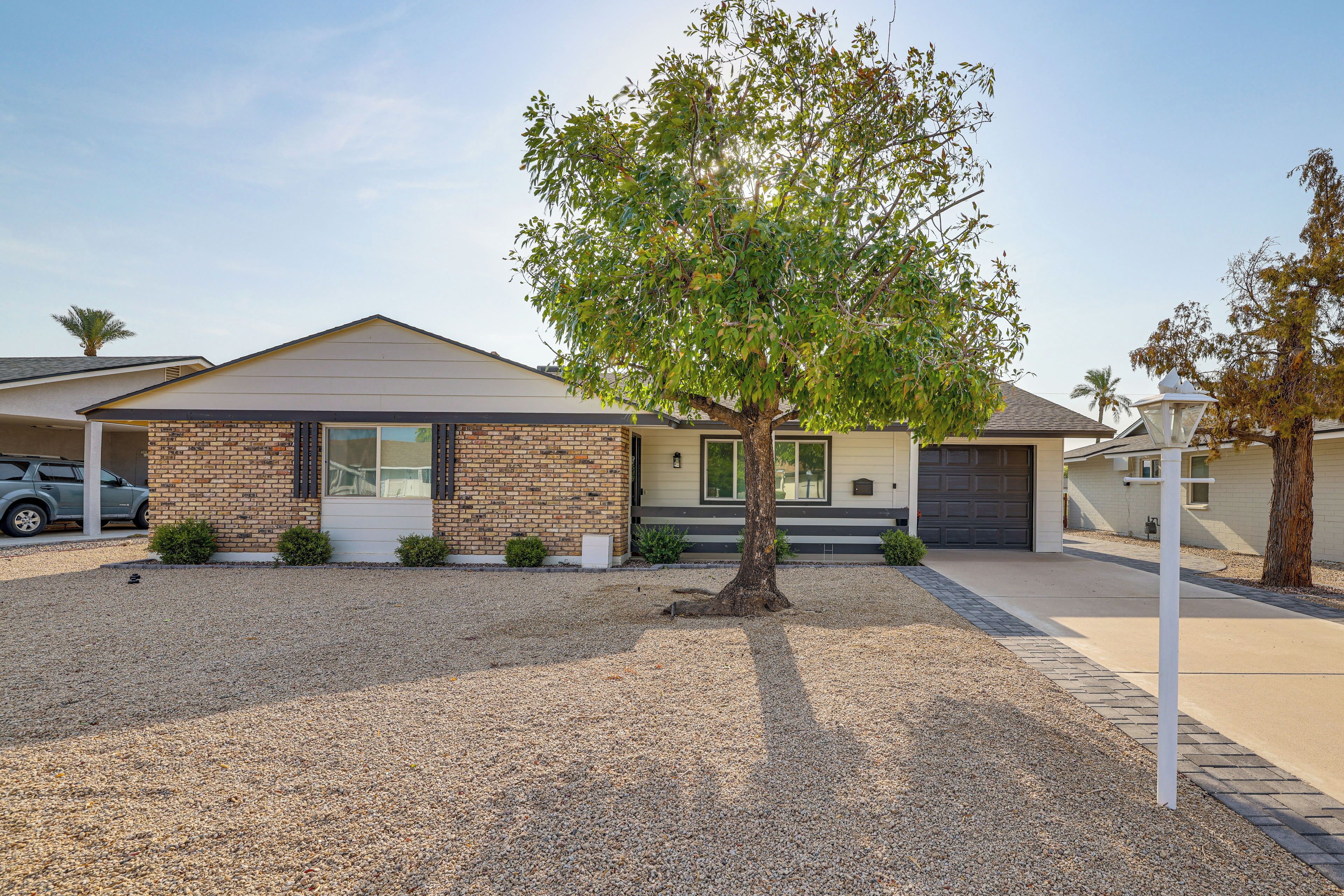 A residential house with a sloped roof, a front garage, and a tree in the front yard.