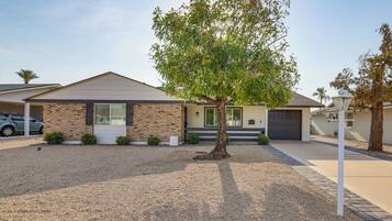 A residential house with a sloped roof, a front garage, and a tree in the front yard.