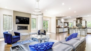 A modern living room with a sofa, a glass coffee table, and a TV mounted on the wall. - Luxe Buckhead Retreat 6 Mi to Dtwn Atlanta (Atlanta)