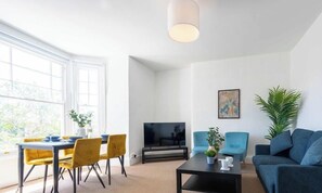 Ein modernes Wohnzimmer mit Essbereich, Flachbildfernseher und großem Fenster.