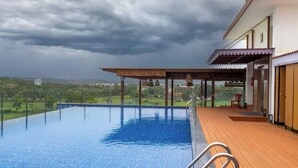 Ein Infinity-Pool auf dem Dach mit Holzterrasse und überdachter Lounge-Ecke.