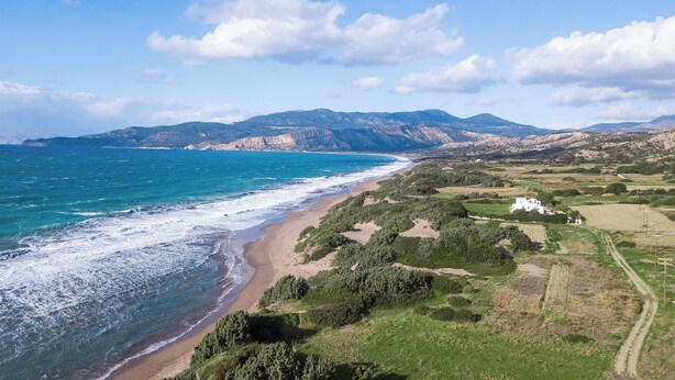 A coastal landscape with a beach, greenery, and distant mountains. - Casa Platoni (Apolakkia)