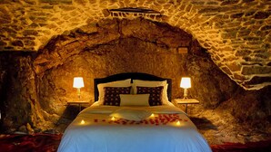Una cama en una habitación con paredes de piedra y dos lámparas de noche.