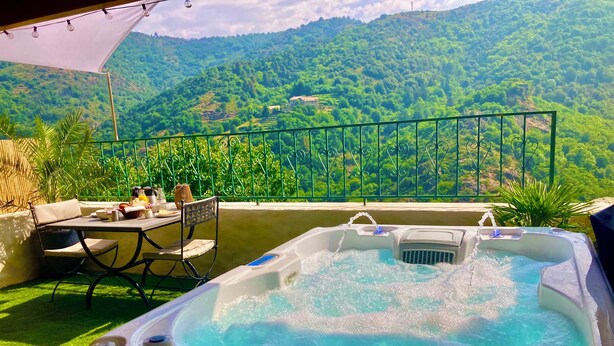 Un jacuzzi en un balcón con vistas a una ladera verde y exuberante.