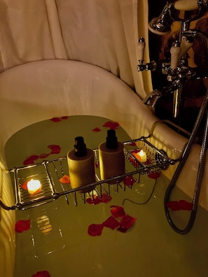 Une baignoire remplie de pétales de roses et entourée de bougies, créant une atmosphère romantique.