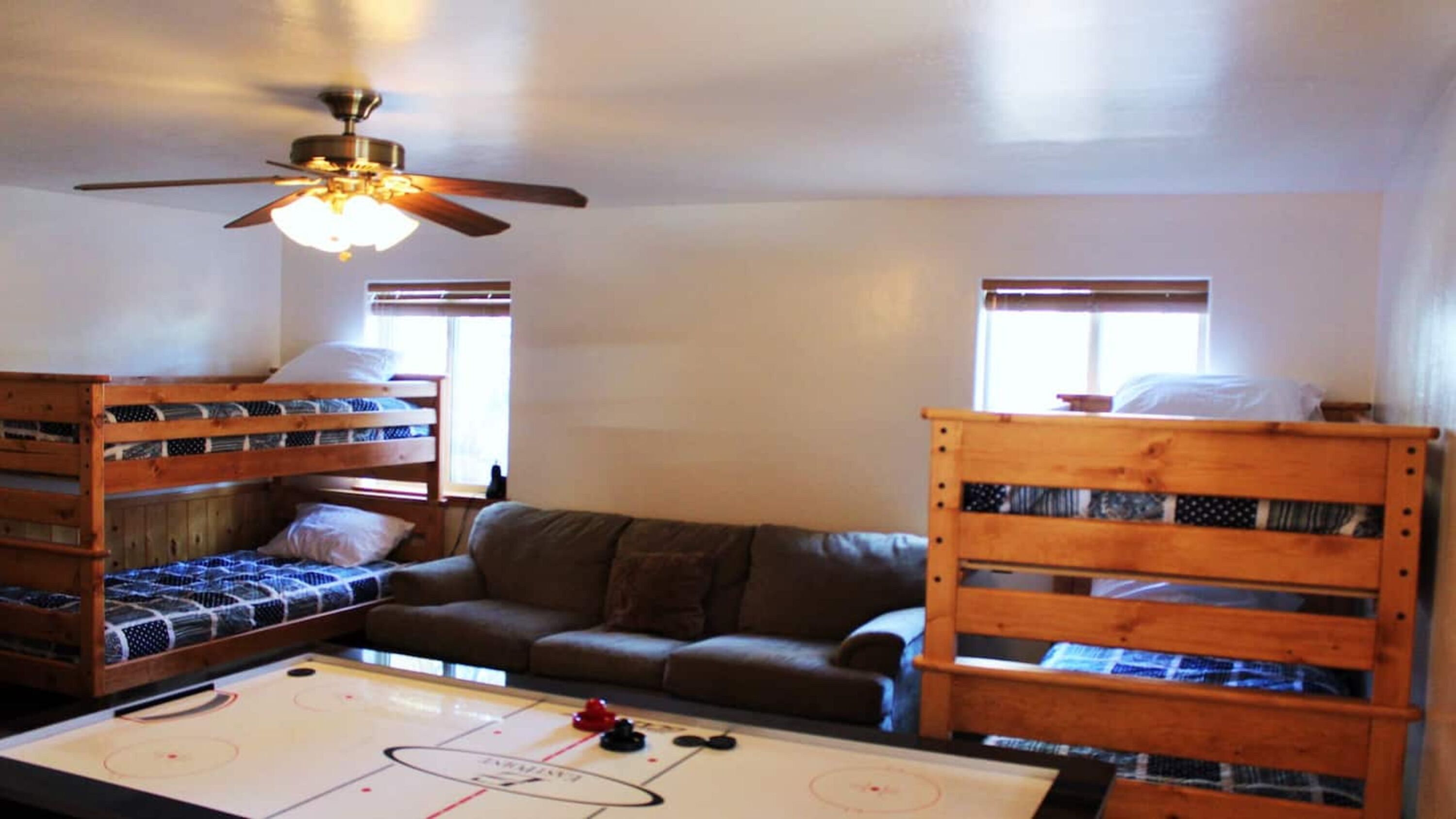 A room with bunk beds, a sofa, and a table with a hockey rink layout.