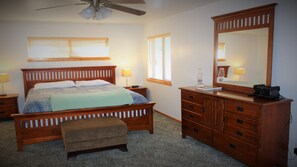 A bedroom with a wooden bed, a nightstand, a dresser with a mirror, and a ceiling fan. - Hot Tub-Game Tables Aspen Glen (Big Bear Lake)