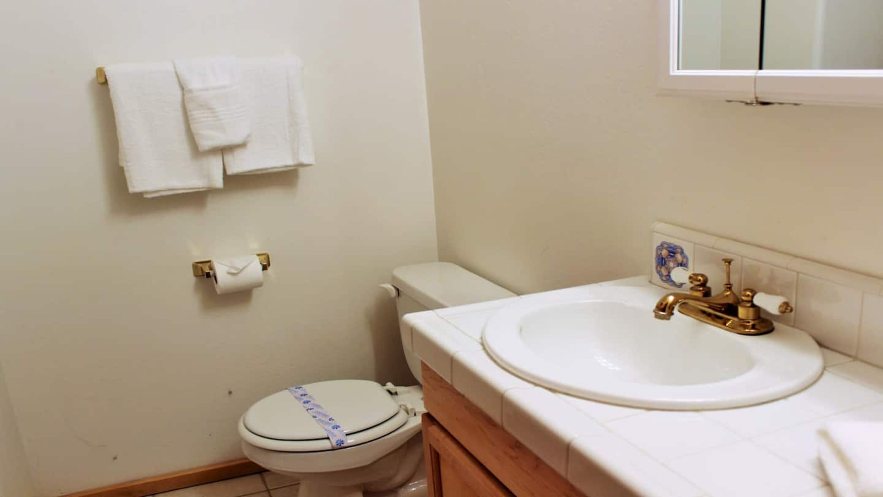 Un baño con inodoro, lavabo y toallero.
