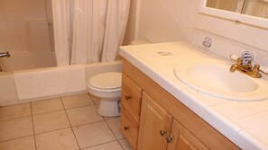 A bathroom with a toilet, a bathtub, and a sink with a mirror above it. - Hot Tub-Game Tables Aspen Glen (Big Bear Lake)