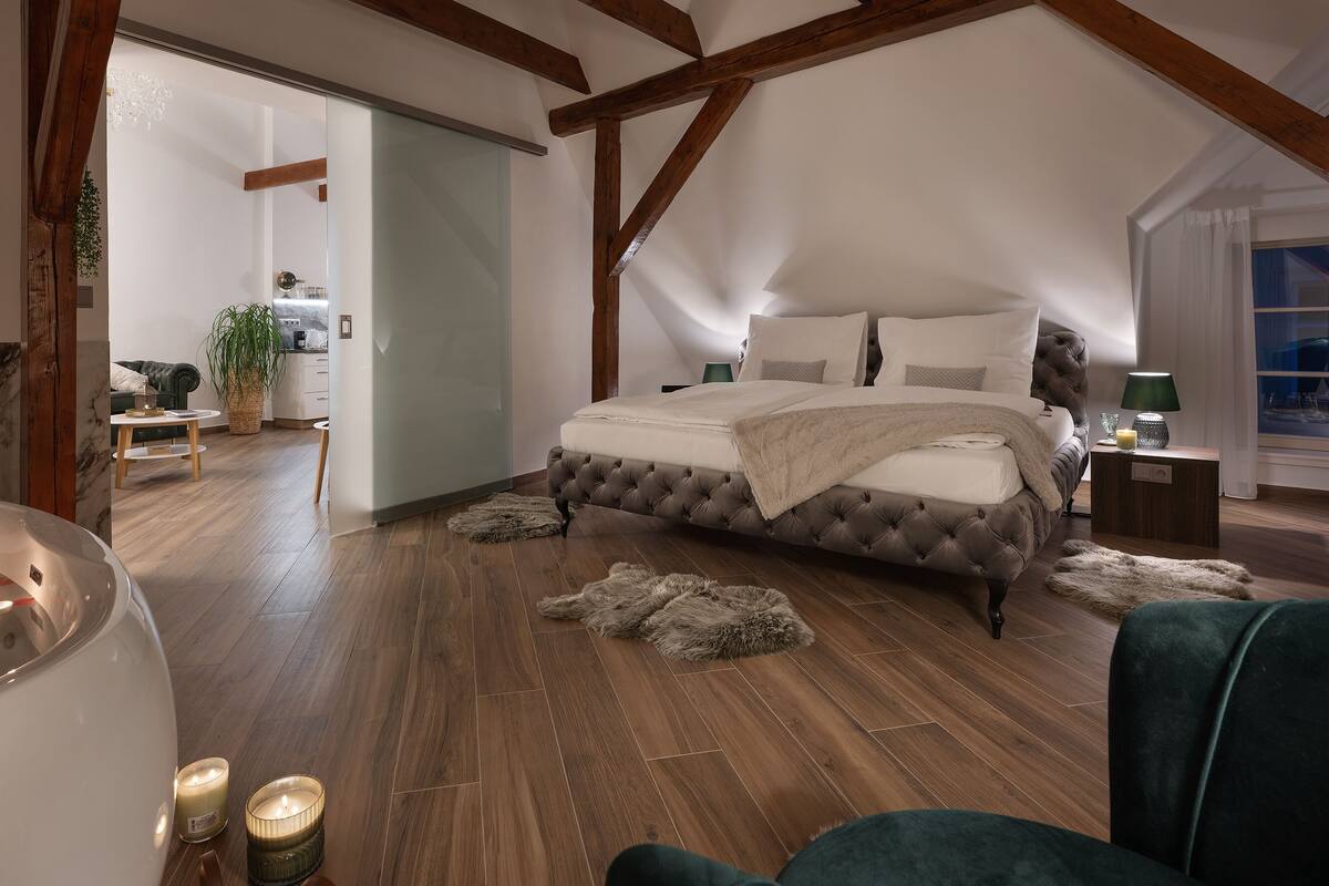 A bedroom with a large bed, a bathtub, and a wooden ceiling.