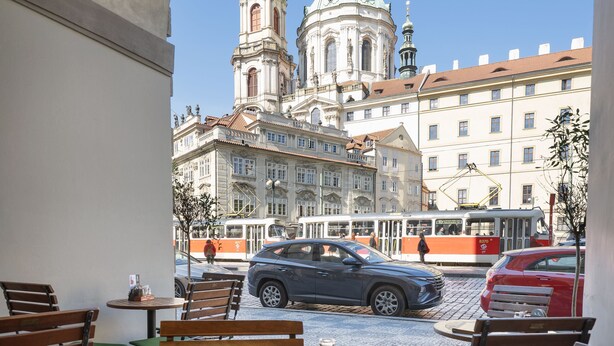 An outdoor dining area with a view of a historic building and a tram. - Kaiserstein Palace Apartments (Prague)