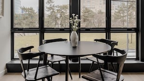 A dining area with a round table, six chairs, and a vase with flowers. - Sosuite One Bed Apt Accessible w Rooftop Gym Laundry (Philadelphia)