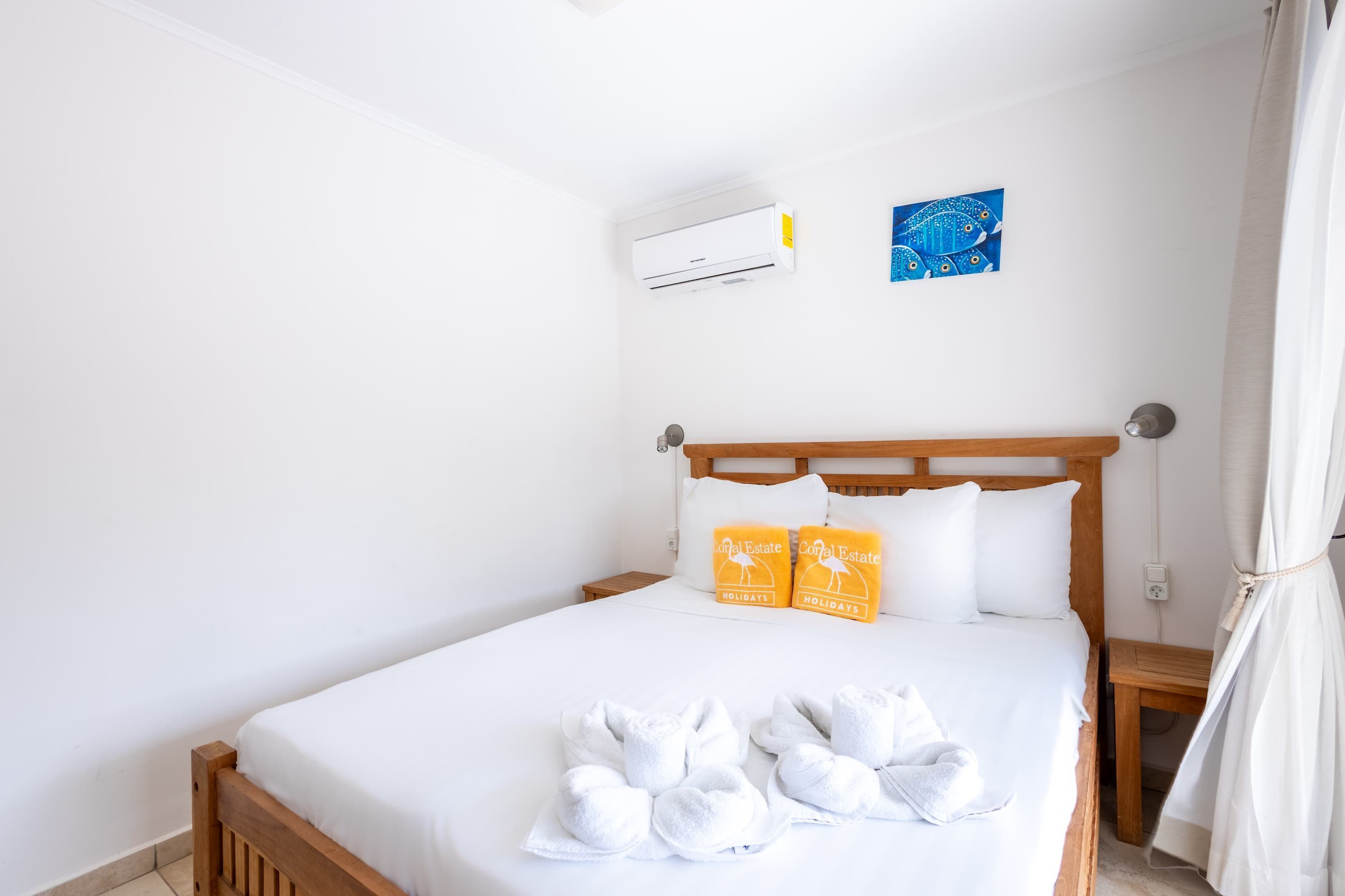 A neatly made bed with white linens and towels, a wooden headboard, and two pillows with a hotel logo.