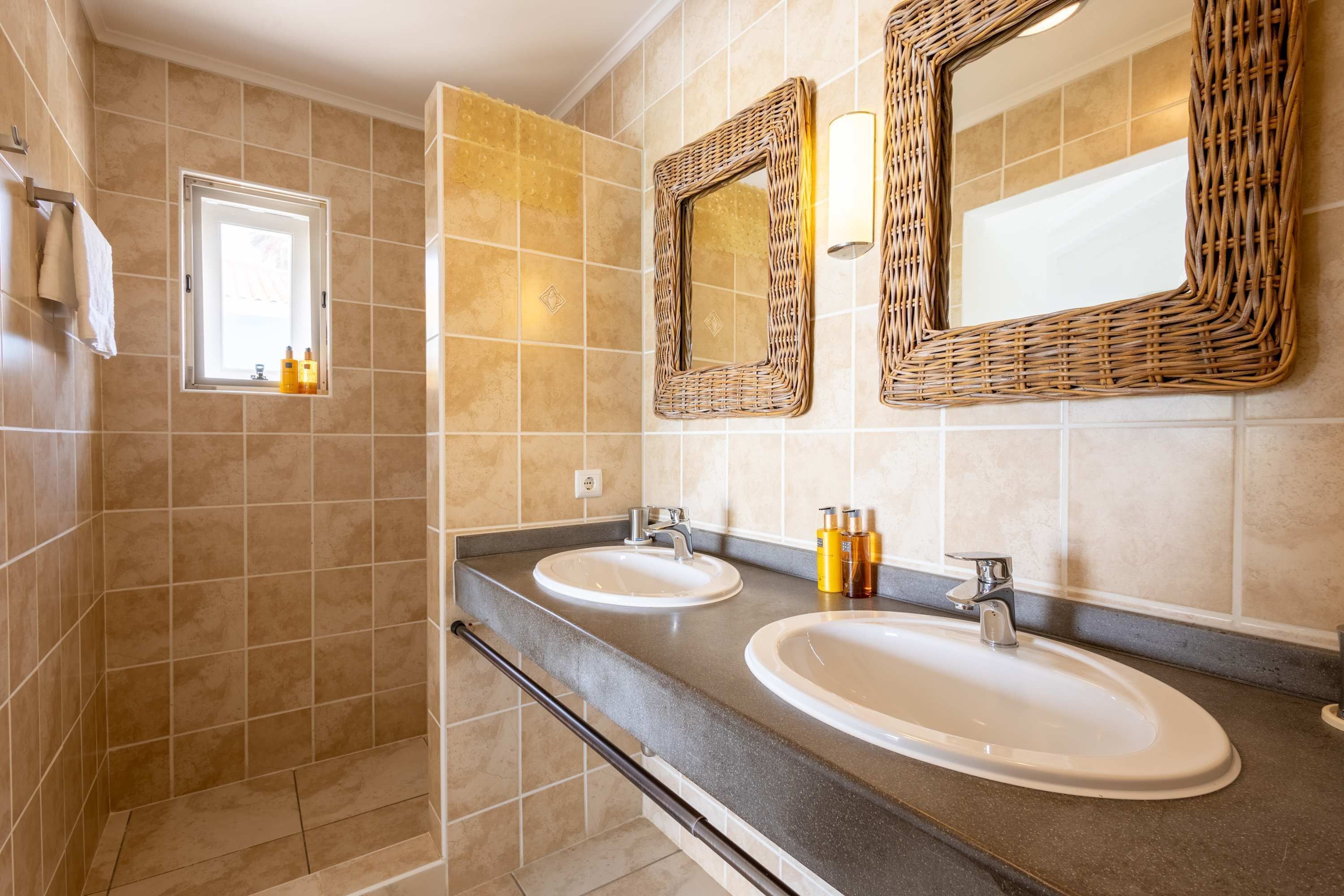 Une salle de bain avec deux lavabos, une fenêtre et une douche.