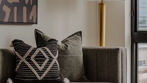 A modern living room with a sofa, a lamp, a coffee table, and a framed abstract artwork. - Sosuite One Bed Apt Plus w Rooftop, Gym, Laundry (Philadelphia)