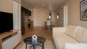 Ein modernes Wohnzimmer mit einem Flachbildfernseher, einer Couch und einem Essbereich mit Stühlen und einem Tisch.