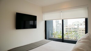 Ein modernes Hotelzimmer mit einem großen Bett, einem flachbildfernseher an der Wand und einem großen Fenster mit Blick auf die Stadt.